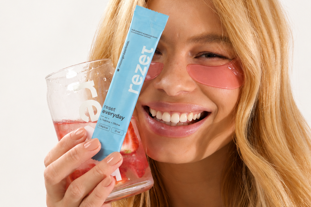 Creator sorrindo com adesivos rosados sob os olhos, segurando um copo de bebida de morango com gelo e um stick de rezet everyday